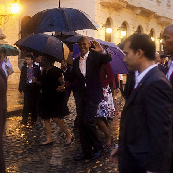 U.S. President Barack Obama, center, waves as he walks in heavy rain during his visit to Havana, Cuba.