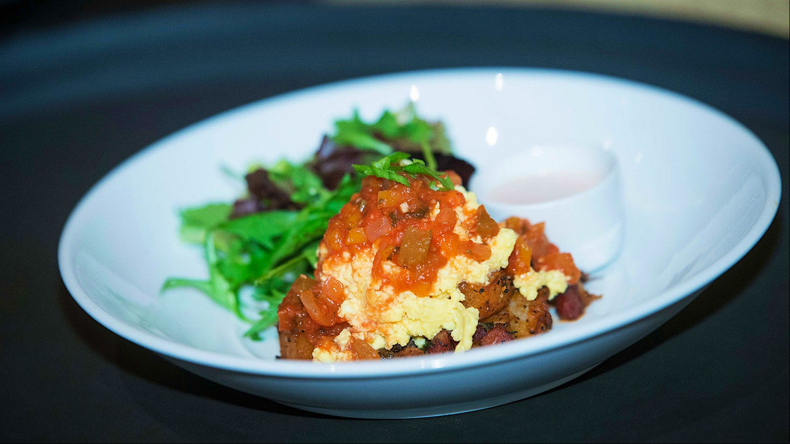 Brisson's dish of Tchoupitoulas Hash, soft scrambled eggs, creole sauce and a small salad of greens.